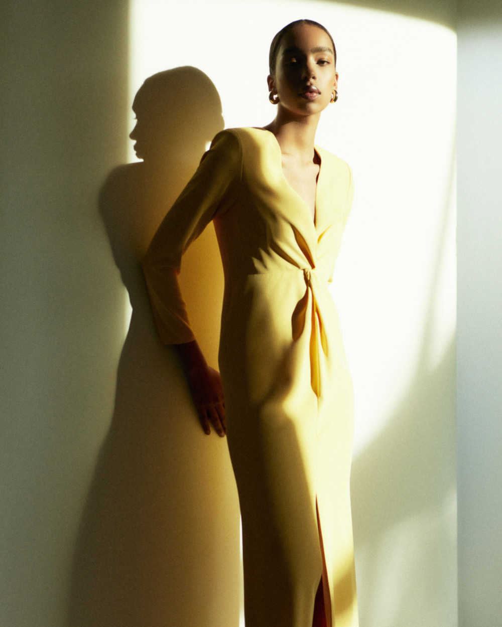 Rhúne SS25 Elisa Dress — full-length yellow draped silhouette bathed in warm light and soft shadow